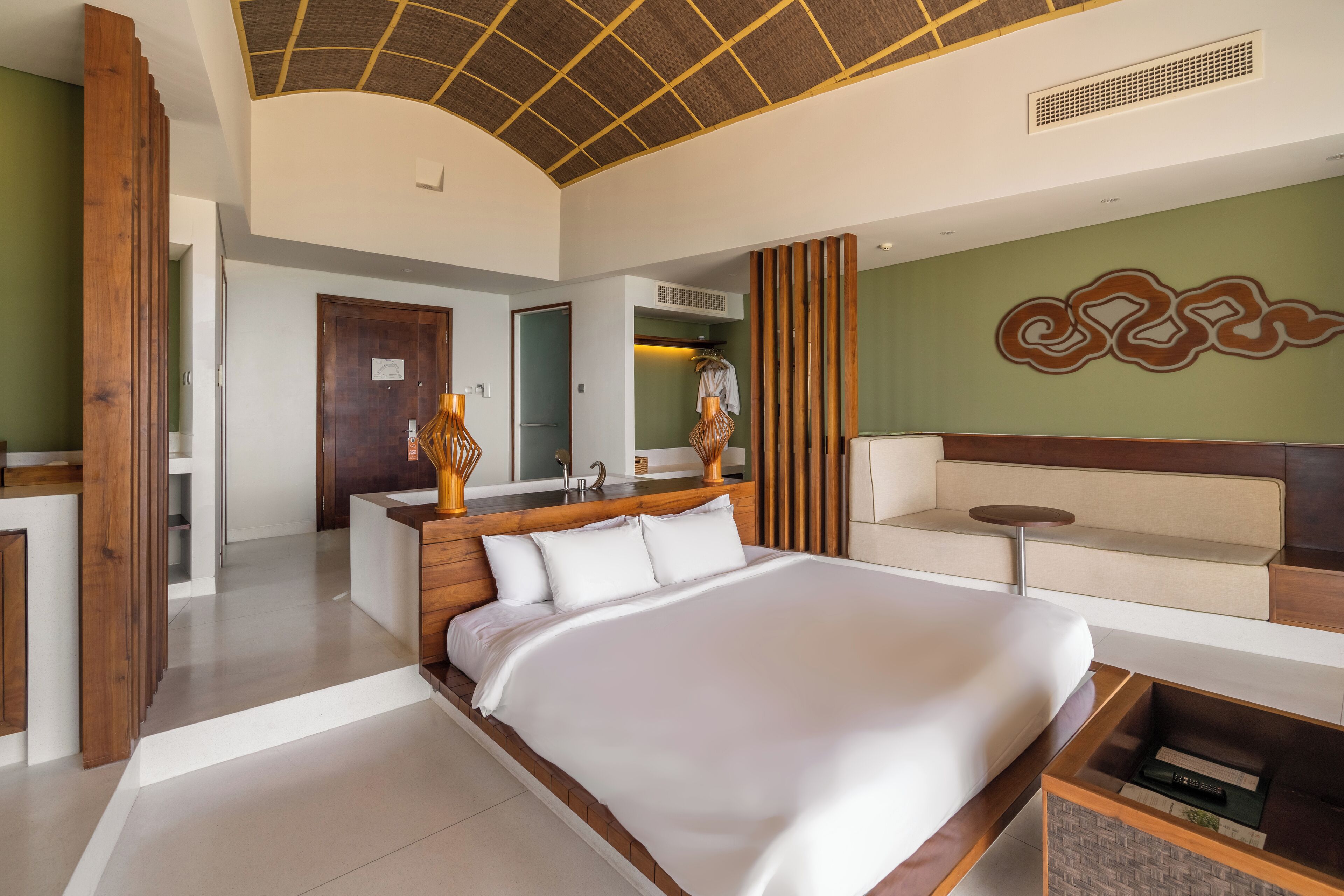 A modern hotel room with a large bed, a seating area, and a wooden accent wall.