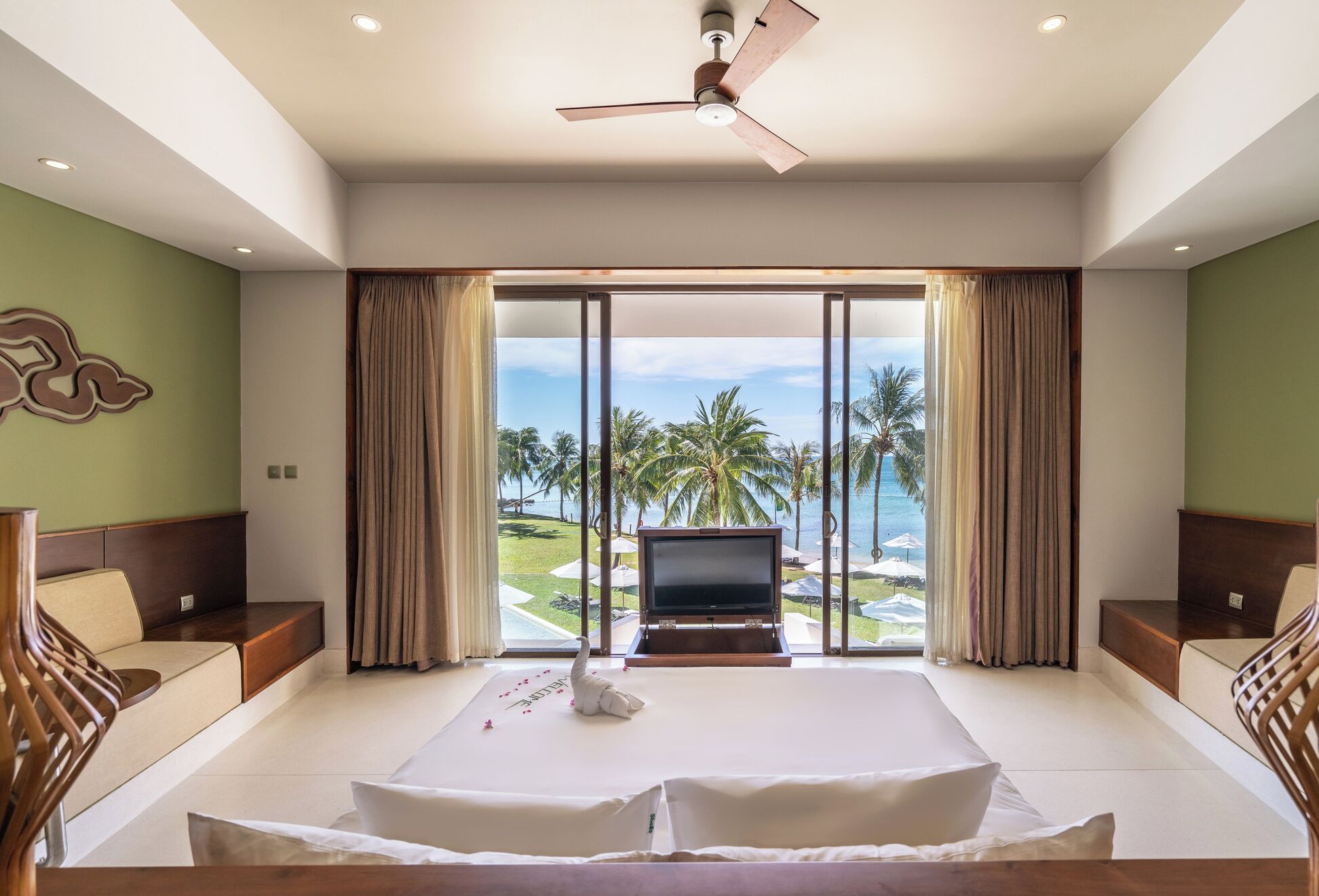 A spacious bedroom with a large bed, a ceiling fan, and a TV.