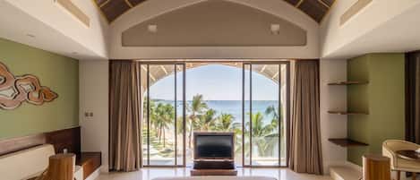 A hotel room with a large bed, a TV, and a view of the ocean.