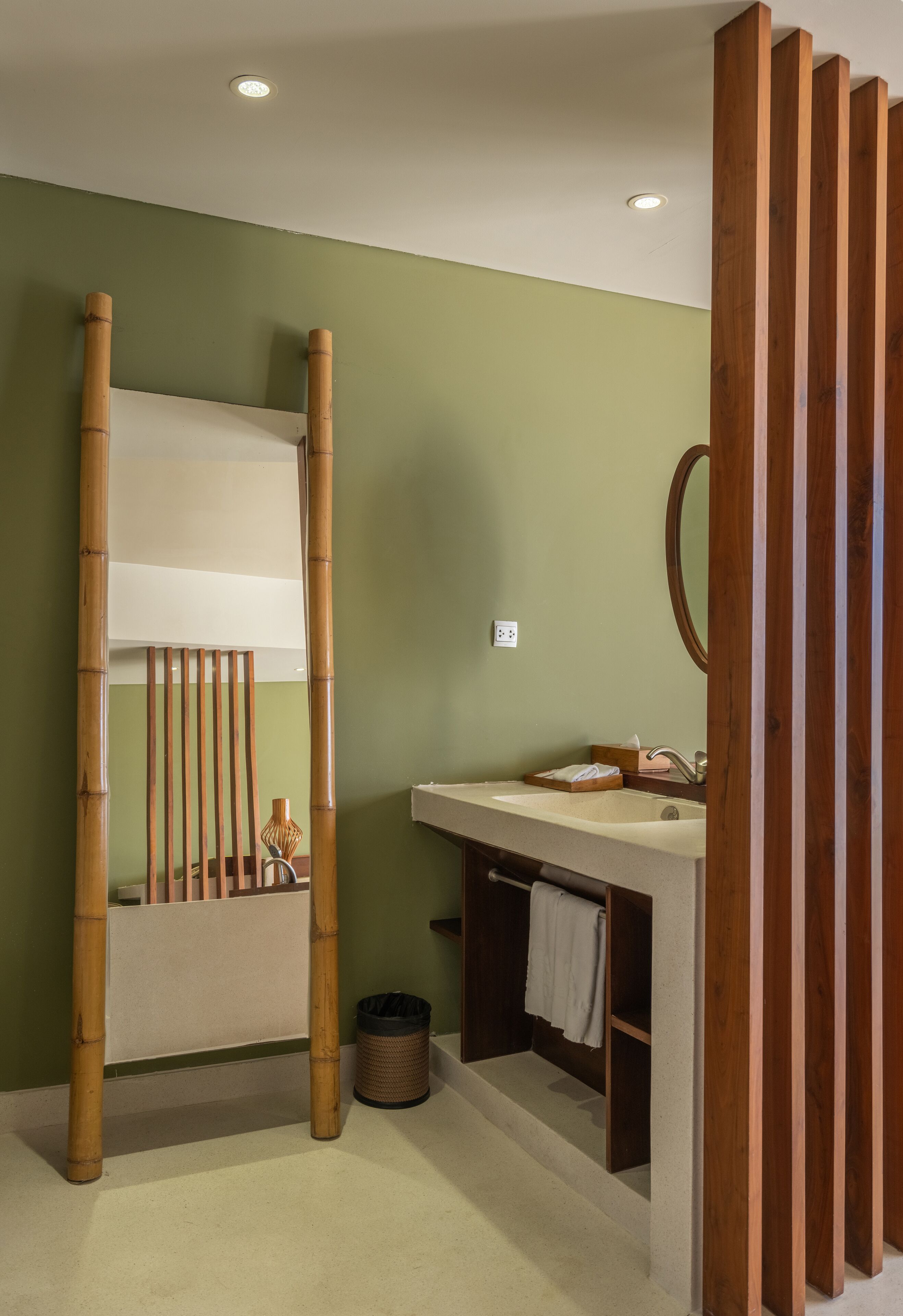 A bathroom with a wooden partition, a sink with a mirror, and a towel rack.
