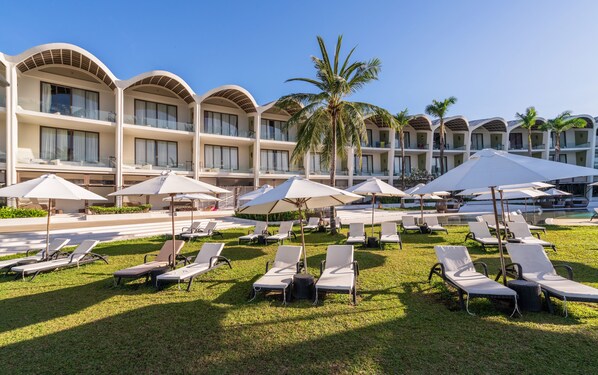 Un hotel con varios balcones, sillas de sol y sombrillas.