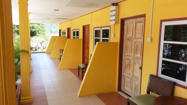 A corridor with yellow walls, wooden doors, and a tiled floor. - MNR Motel (Langkawi)