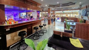 Interior de un restaurante con barra, mesas y ventilador de techo.