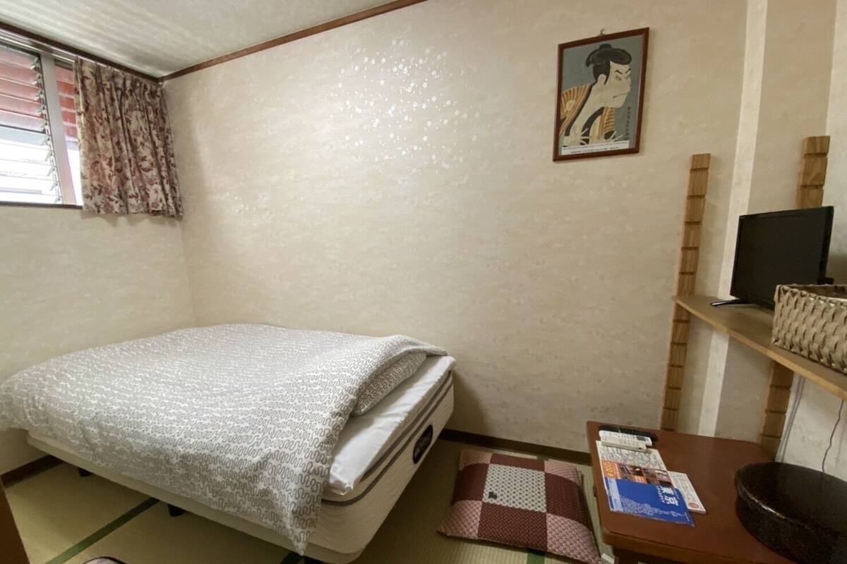 Een kleine, verzorgde kamer met een bed, een bureau, een stoel en een televisie.