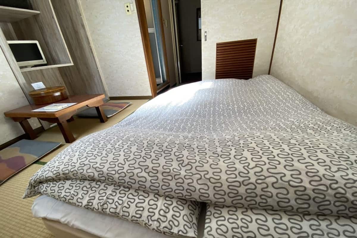Een hotelkamer met een bed, een houten bureau en een televisie.