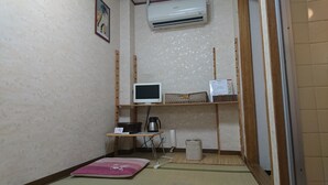 A small room with a tatami mat, a television on a shelf, a heater, and a trash bin. - Asakusa Ryokan Toukaisou (Tokyo)