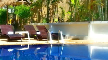 Una piscina al aire libre, sillones reclinables de piscina