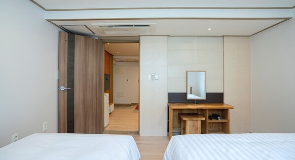 Una habitación de hotel con dos camas, un escritorio de madera con un espejo y un armario.