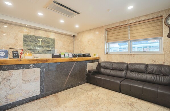 A reception area with a marble counter, a leather sofa, and a window with blinds.