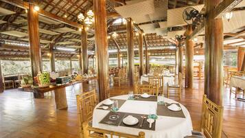 Un'ampia sala ristorante con travi in legno e tavoli apparecchiati per la cena.