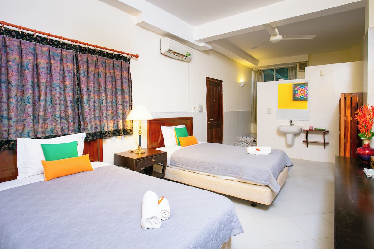 A hotel room with two beds, a bathroom, and a ceiling fan.