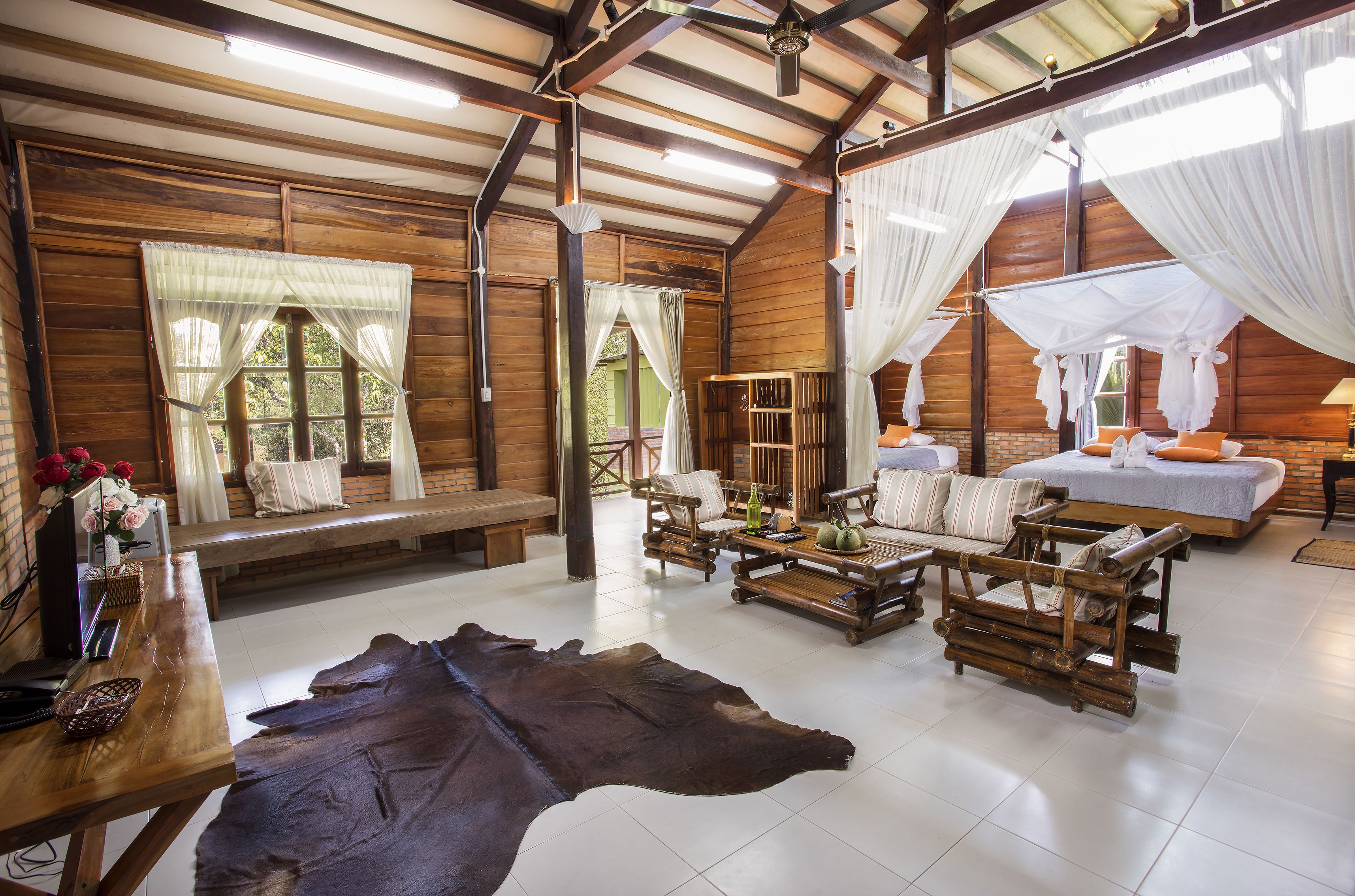 A rustic wooden room with a large leather rug, wooden furniture, and a bed with a canopy.