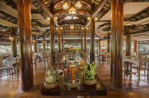 A spacious dining area with wooden beams and a high ceiling, featuring a long table set for a meal. - Cat Tien Jungle Lodge (Nam Cat Tien)