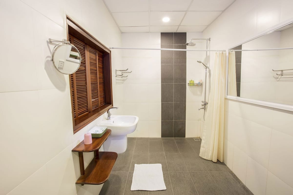 A bathroom with a sink, mirror, shower, and a towel on the floor.
