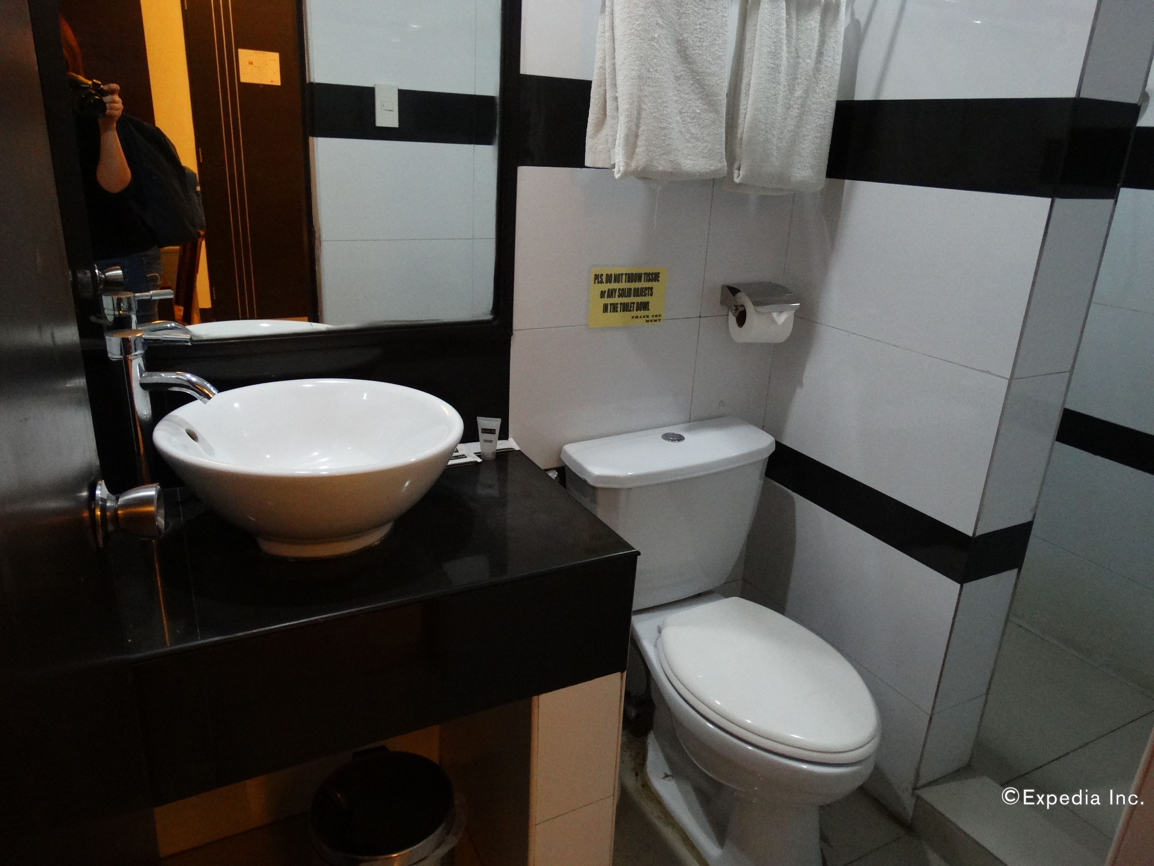 Ein Badezimmer mit weißem Waschbecken, schwarzer Arbeitsplatte, weißer Toilette und einem Handtuch an der Wand.