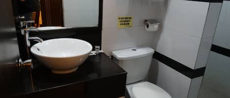 Ein Badezimmer mit weißem Waschbecken, schwarzer Arbeitsplatte, weißer Toilette und einem Handtuch an der Wand.