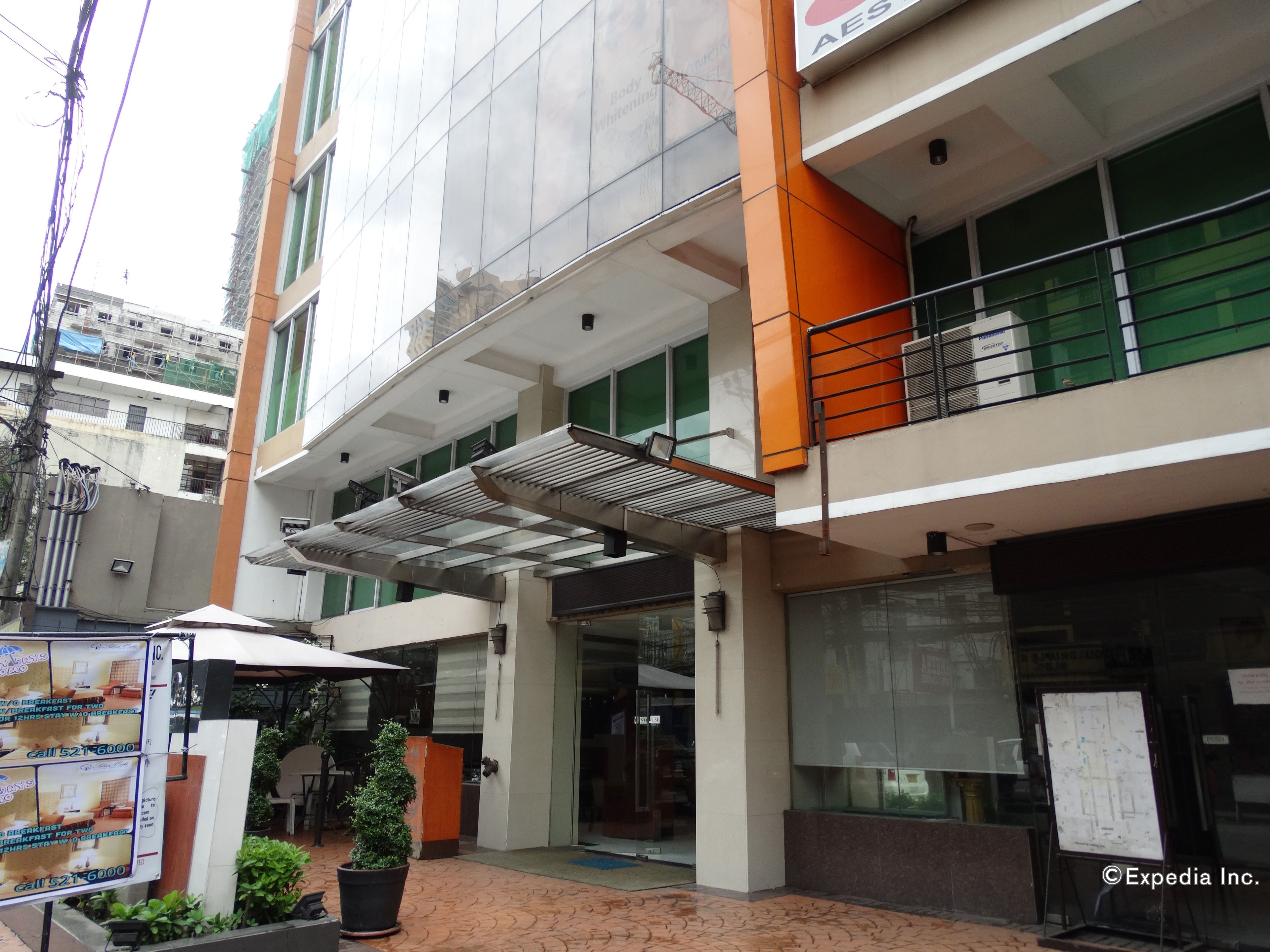 A hotel entrance with a covered walkway, a signboard, and a potted plant.