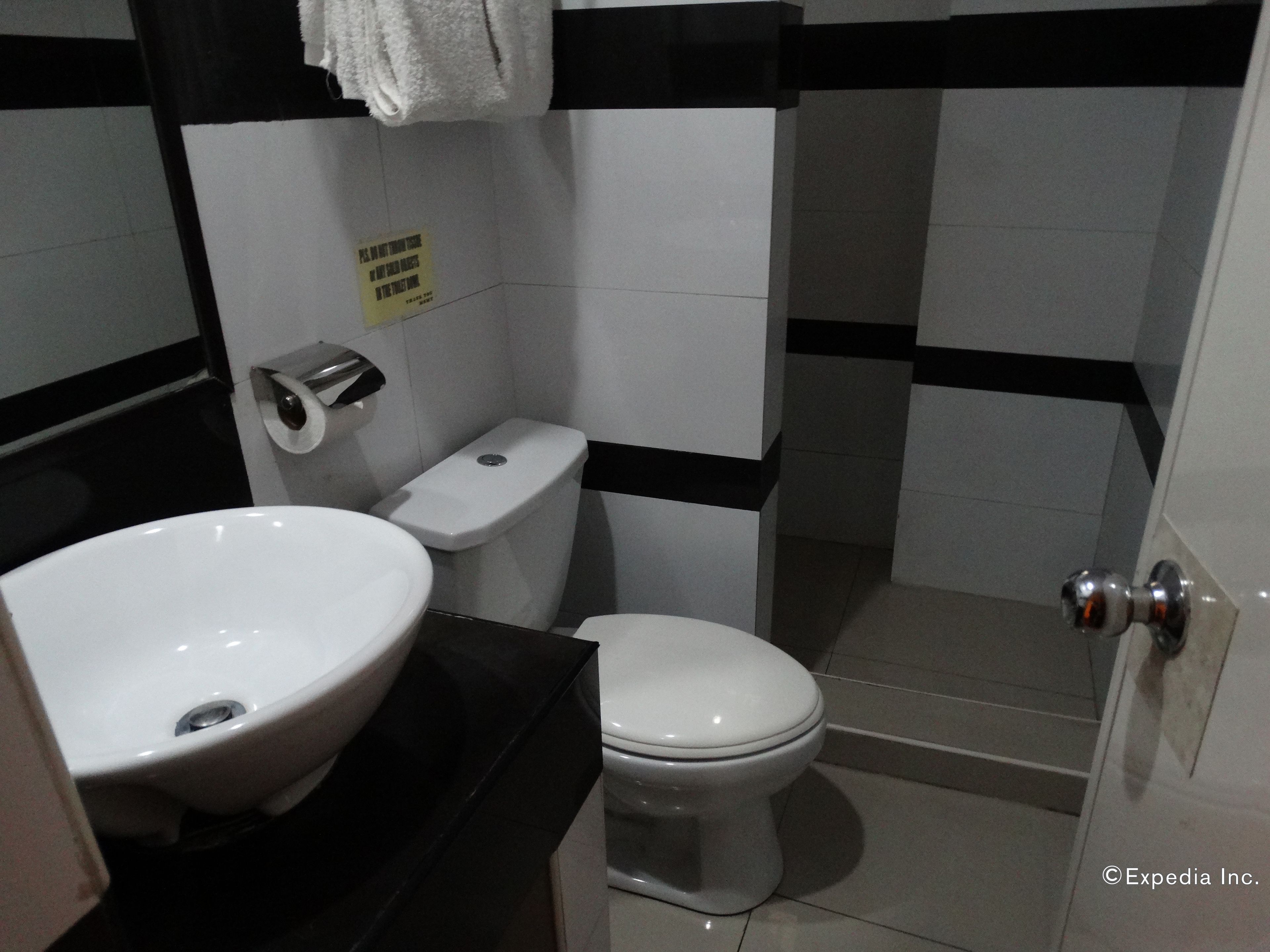 A small bathroom with a toilet, sink, and a towel hanging on the wall.