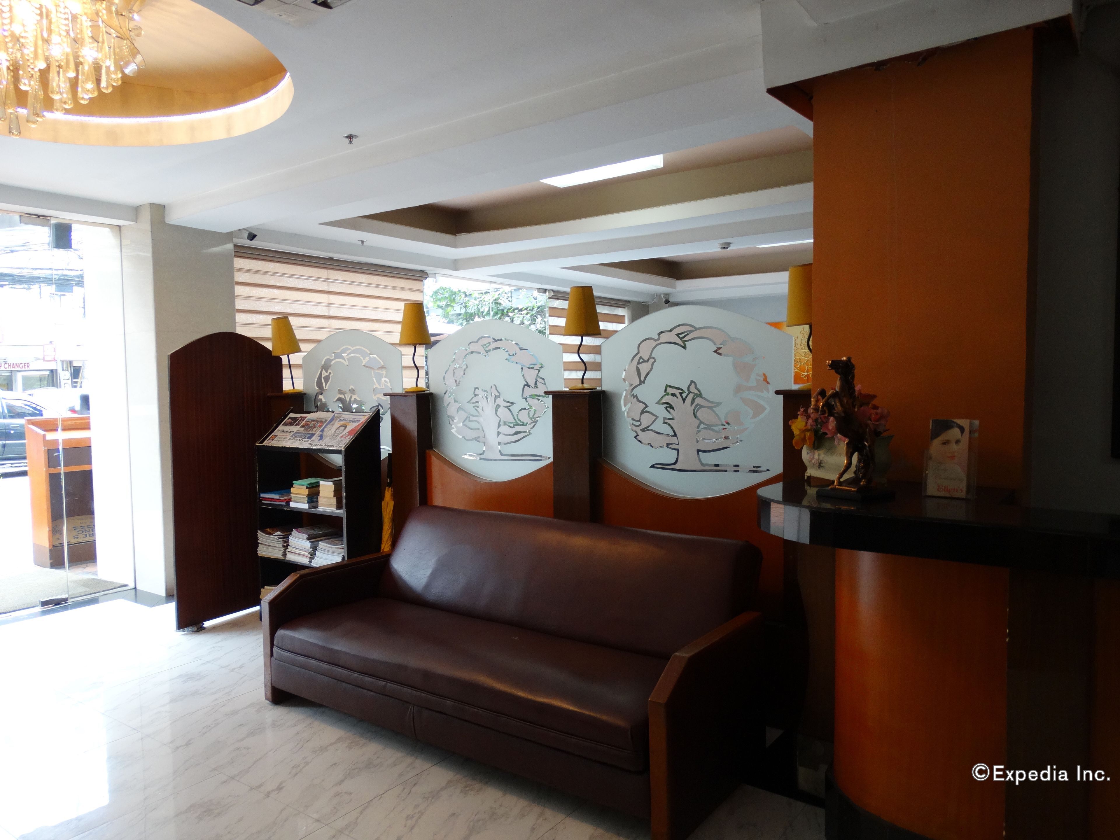 A reception area with a brown leather sofa, a wooden reception desk, and decorative wall art.