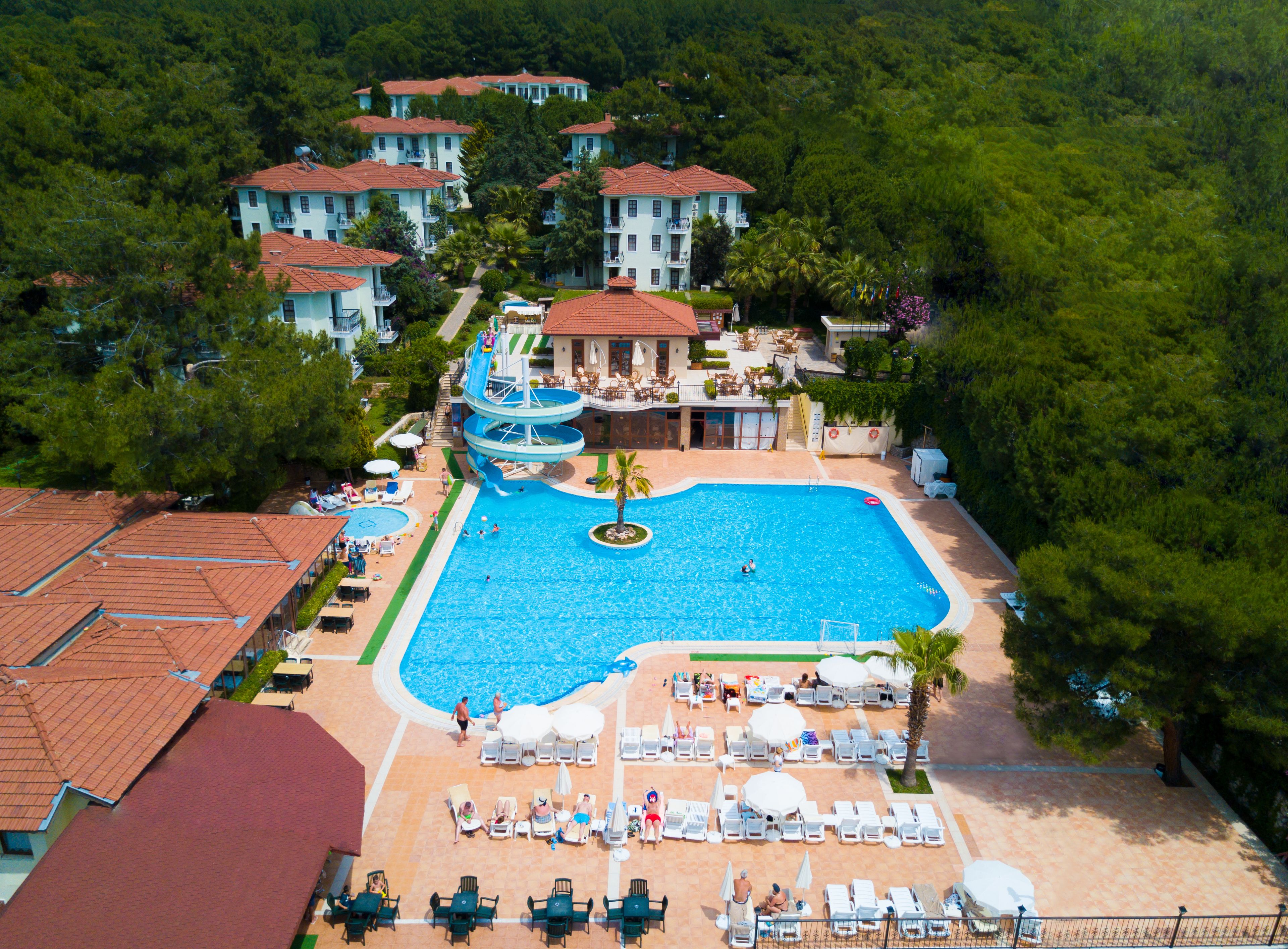 A resort with a large swimming pool, multiple buildings, and a well-maintained garden area.
