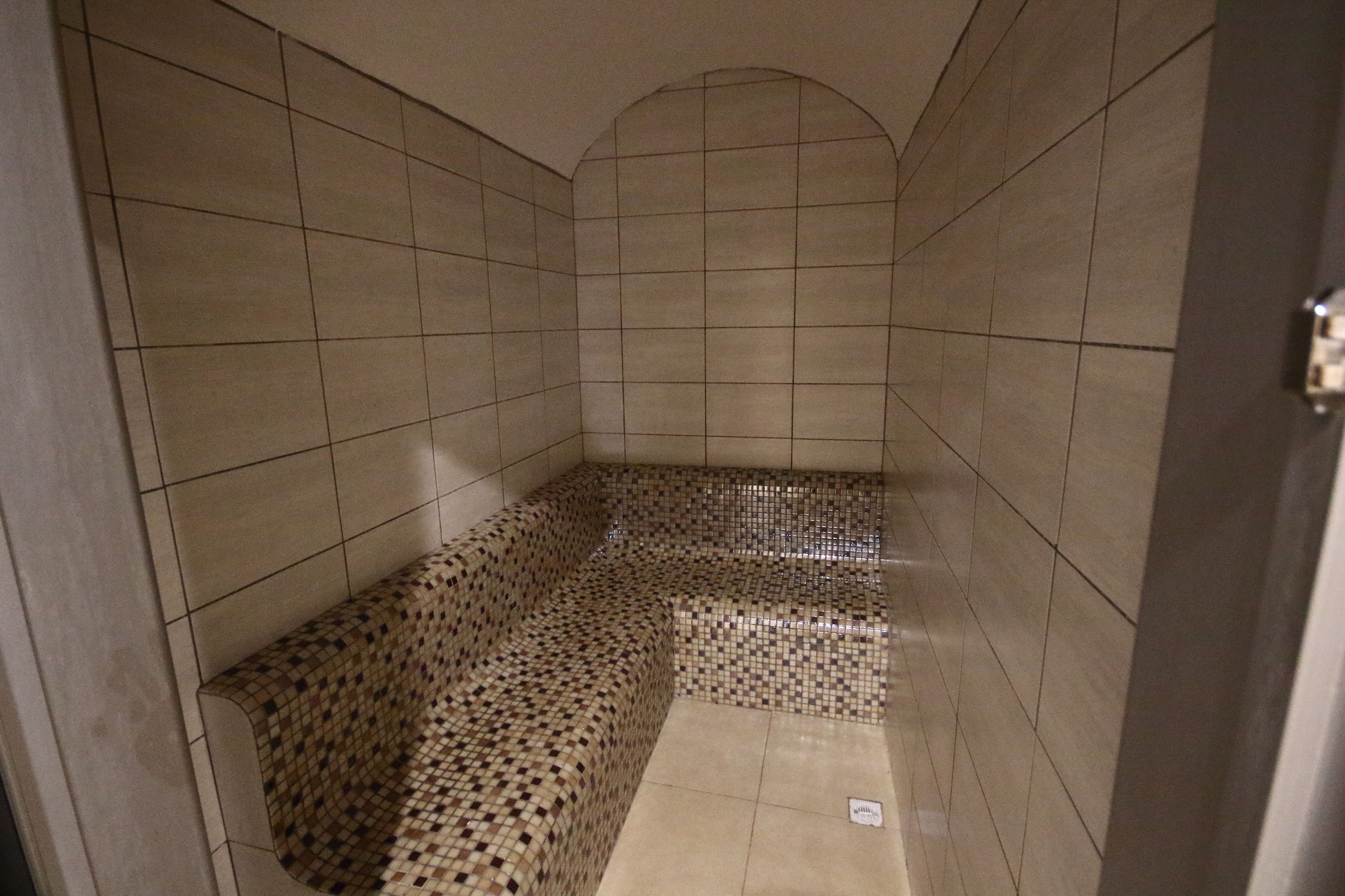 A tiled room with a bench and a tiled floor.