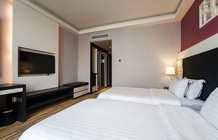A hotel room with two beds, a TV, a desk, and a door leading to a bathroom.