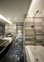 Un baño moderno con suelo de mármol, un espejo grande, una bañera y zona de ducha.