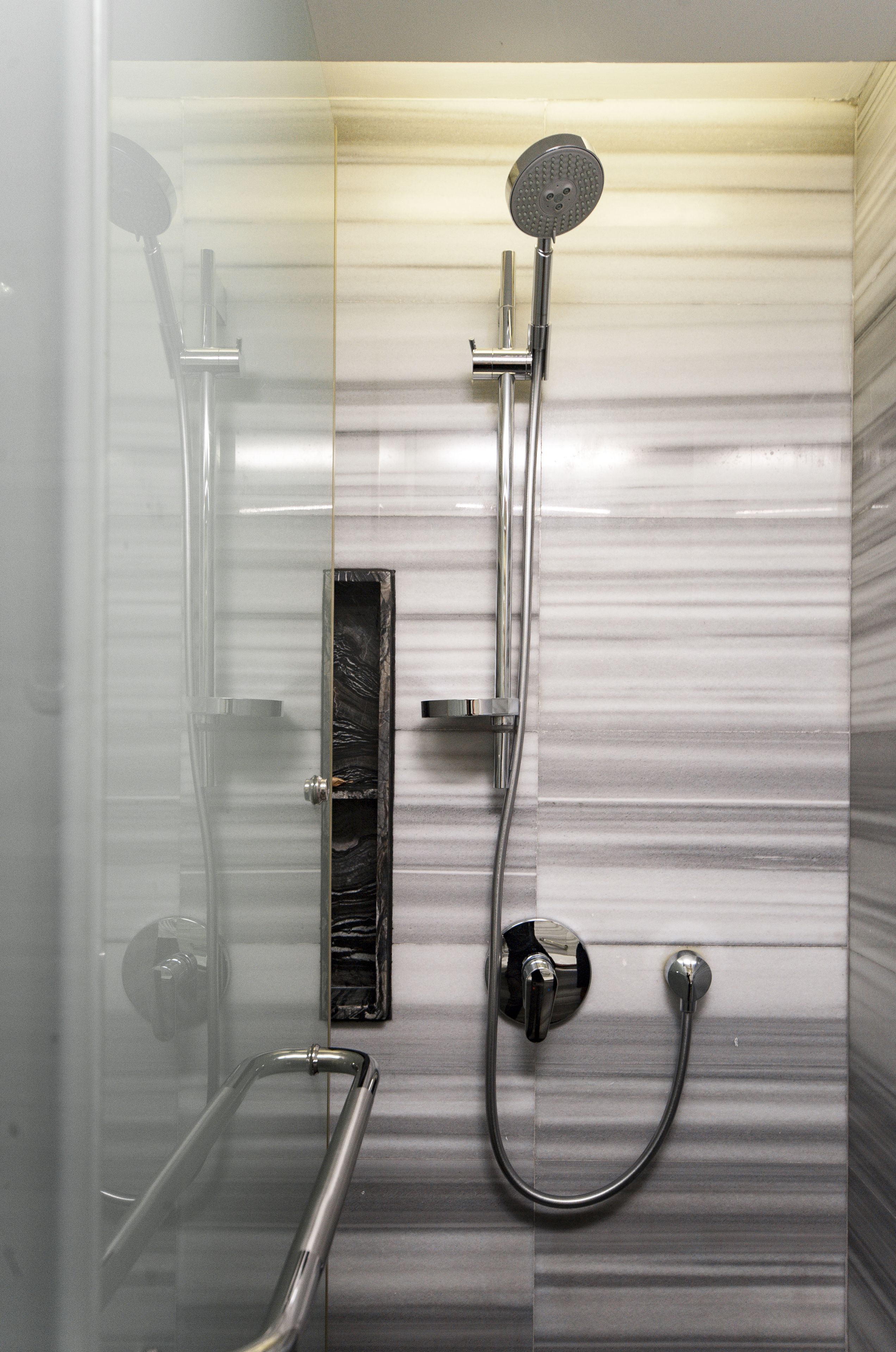 A shower with a handheld showerhead and a wall-mounted faucet.