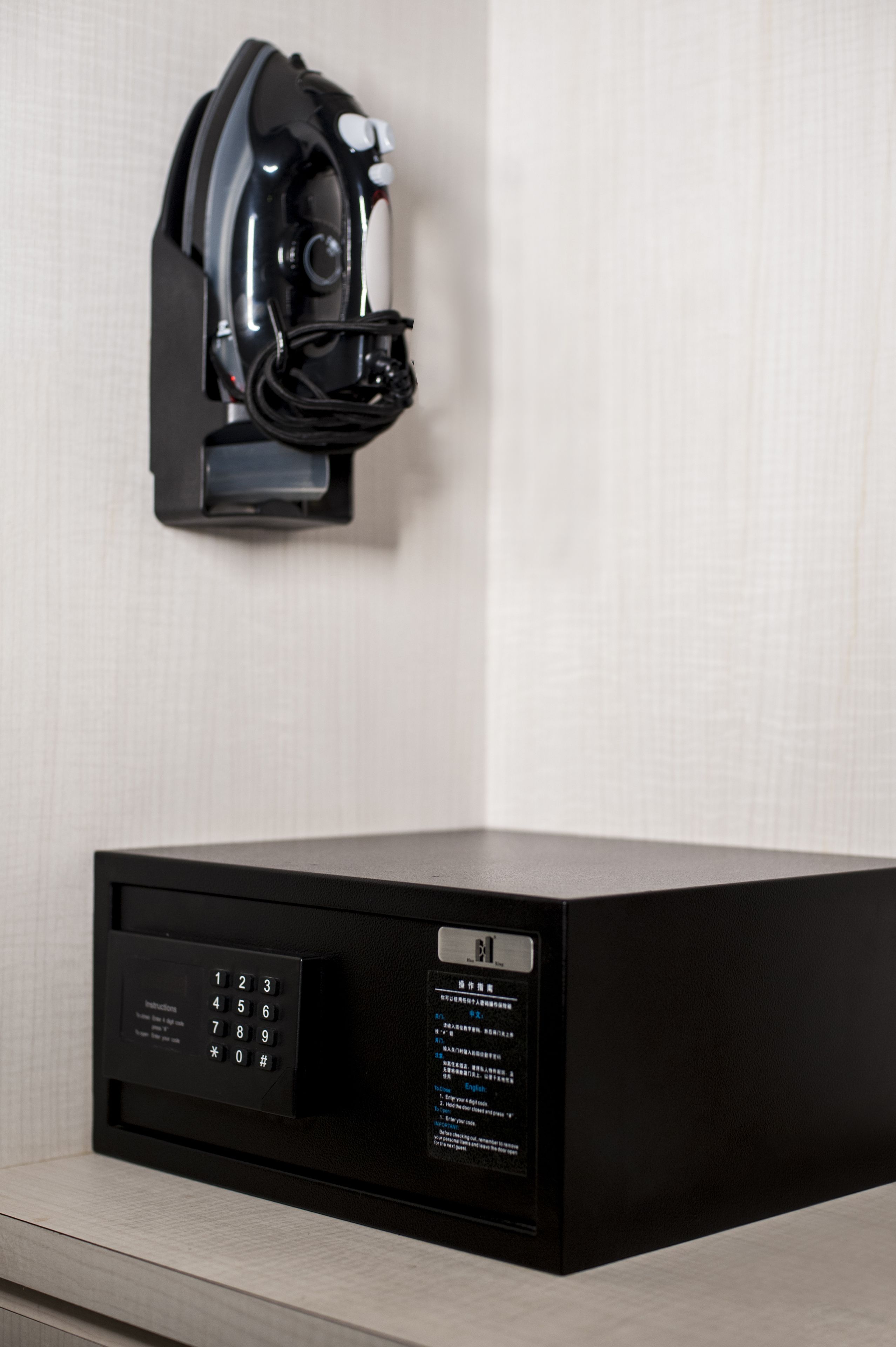 A black coffee machine mounted on a wall with a control panel below it.