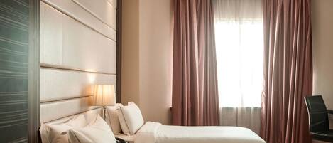 Habitación de hotel con dos camas, un escritorio y una silla.