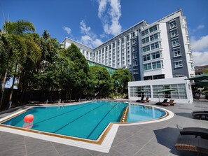 A hotel with a swimming pool, lounge chairs, and a modern building with multiple floors and large windows. - Promenade Hotel Kota Kinabalu (Kota Kinabalu)