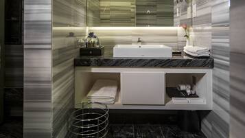 A modern bathroom with a large mirror, a white sink, and a marble floor.
