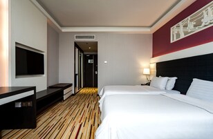 Habitación de hotel con una cama grande, un escritorio, un televisor de pantalla plana y una obra de arte colgada en la pared.