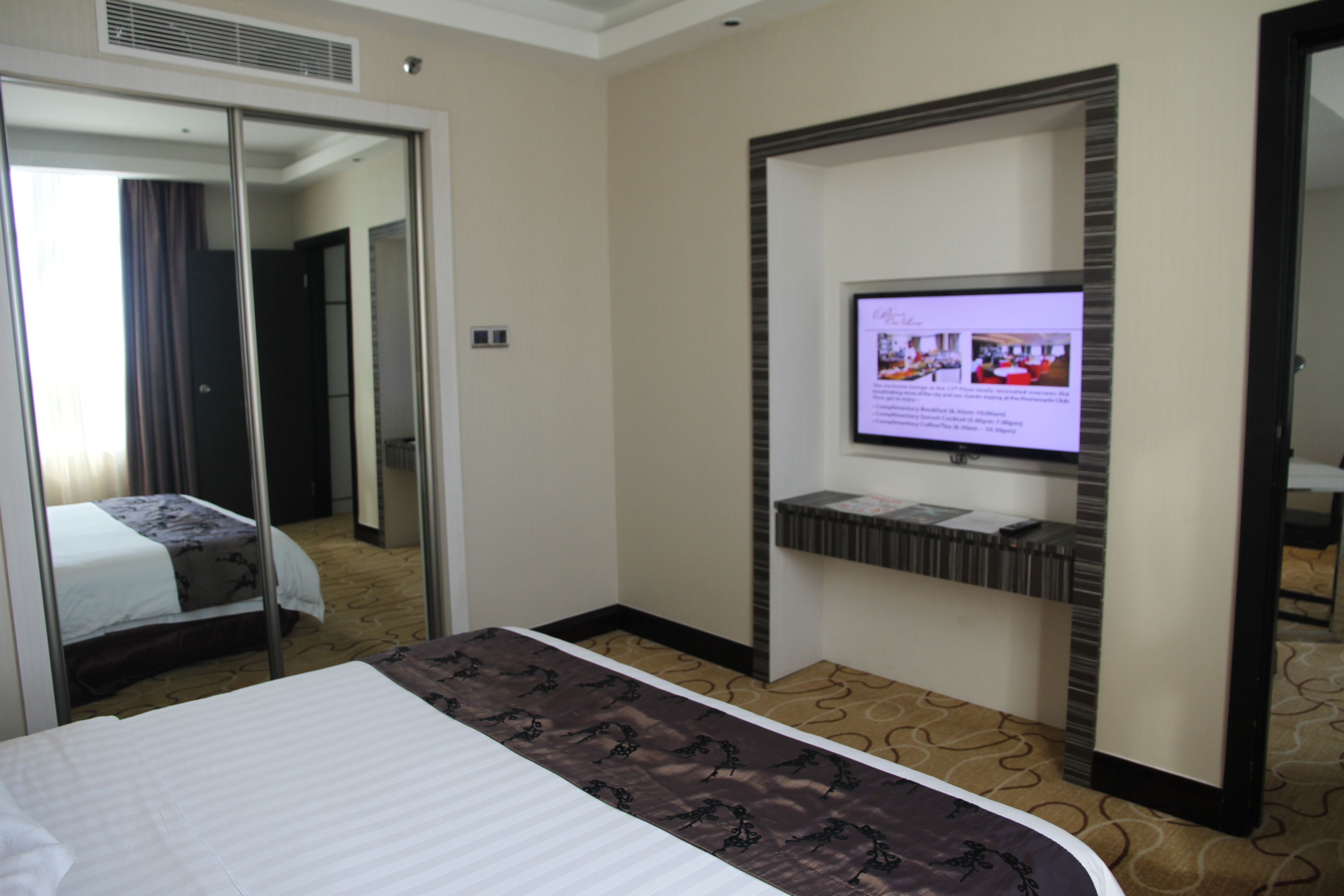 Une chambre d’hôtel avec un lit, un téléviseur fixé au mur et un miroir qui reflète la pièce.