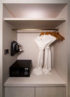 A compact, well-organized closet with a hanging rack for clothes, a black electronic device, and a white robe.