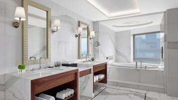 A modern bathroom with two sinks, a large mirror, and a bathtub.