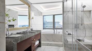 A modern bathroom with a dual sink vanity, a large mirror, a glass-enclosed shower, and a bathtub.