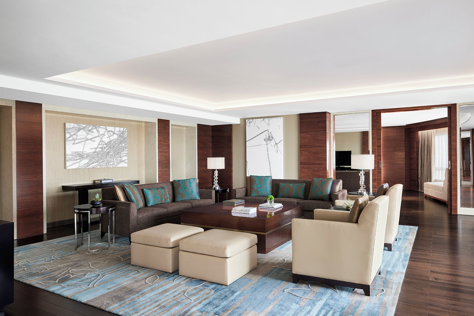 A modern hotel lobby with a large seating area, a coffee table, and a television.