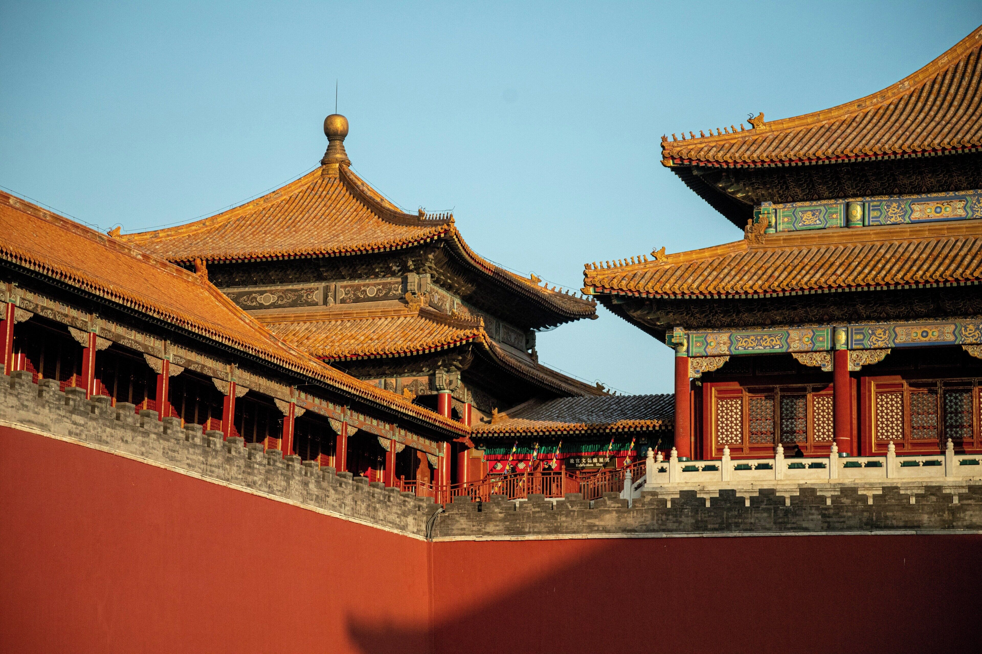 A traditional Chinese building with ornate roofs and a red wall.
