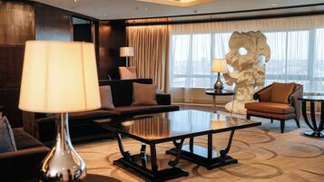 A modern hotel lobby with a sofa, armchairs, a coffee table, and a decorative sculpture.