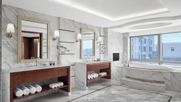 A modern bathroom with marble floors, dual sinks, and a large bathtub.