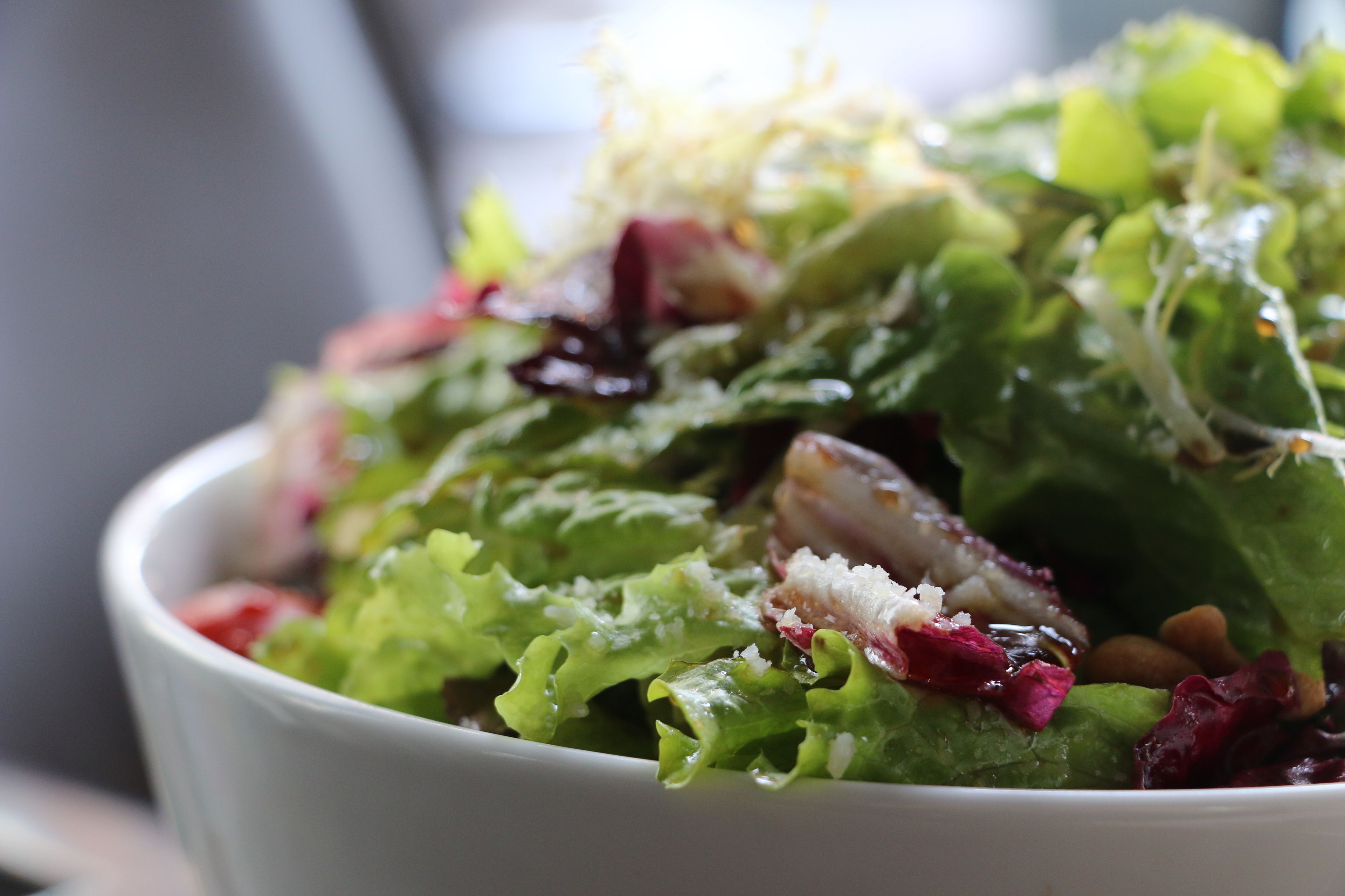 A bowl of salad with various greens and toppings.