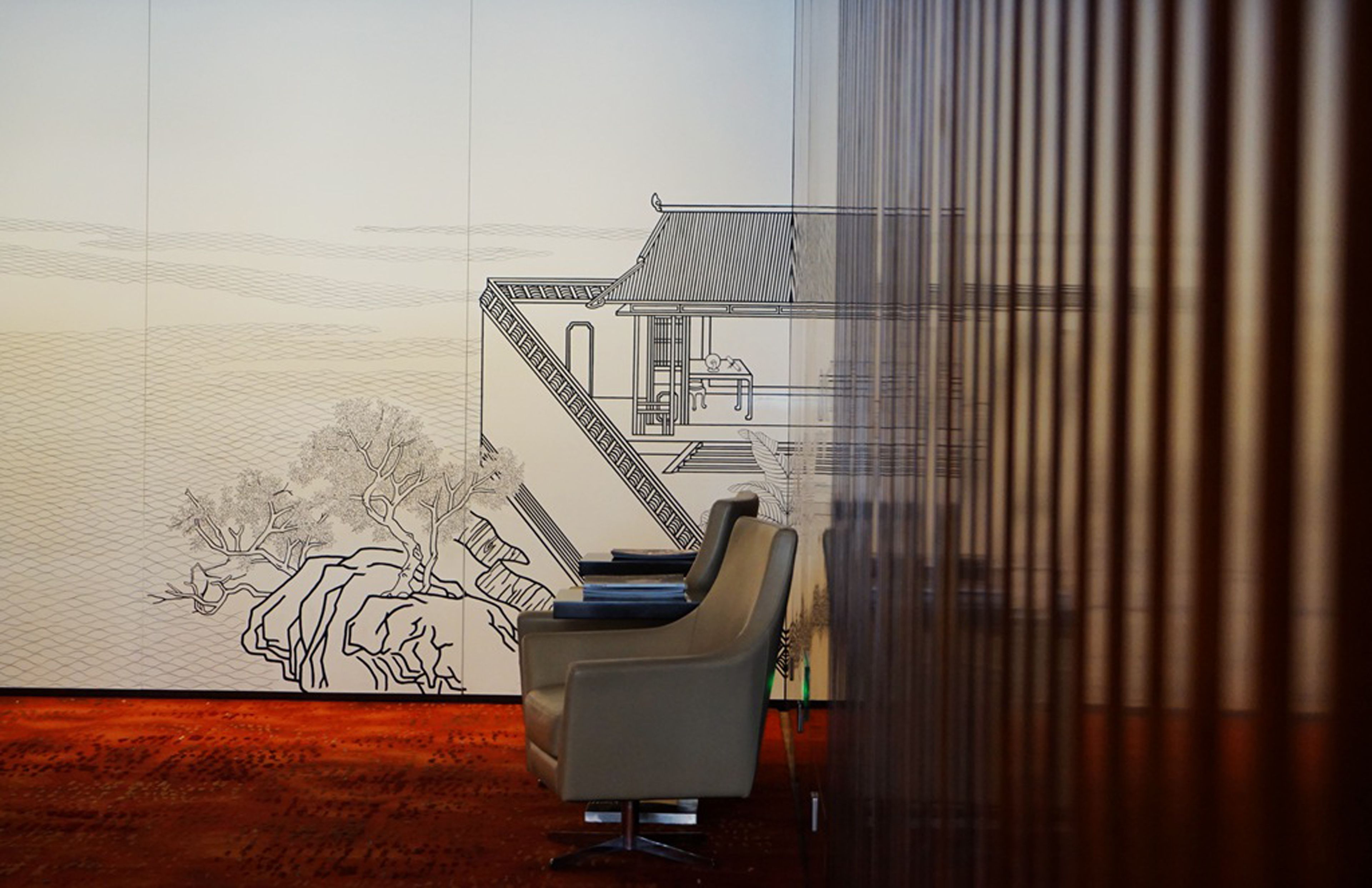 A modern interior with a large wall mural, a seating area, and a staircase.