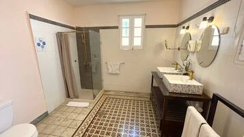Ein Badezimmer mit Dusche, Toilette, Waschbecken und einem gemusterten Boden.