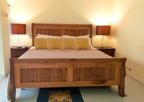 Una cama de madera con cabecera, dos mesitas de noche y un tapete estampado.