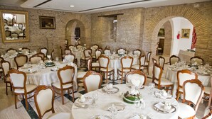 A banquet hall with round tables, white tablecloths, and wooden chairs. - Hotel Castello di Septe (Mozzagrogna)