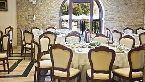 A dining area with multiple tables set for a meal, surrounded by wooden chairs with cushioned seats. - Hotel Castello di Septe (Mozzagrogna)