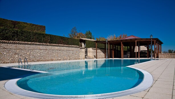 A swimming pool with a stone wall and a gazebo. - Hotel Castello di Septe (Mozzagrogna)