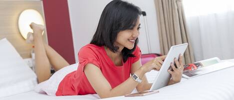 A person lying on a bed using a tablet.