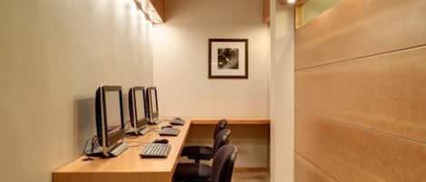 A conference room with a long table, multiple computer monitors, and black office chairs.